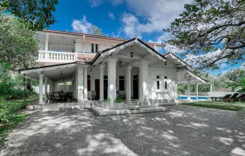 a white house with a patio in front of it at Tara Garden Sri Lanka - luxury colonial villa in Danwattegoda