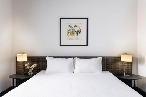 a bedroom with a white bed with two lamps at Edit Auckland Central in Auckland