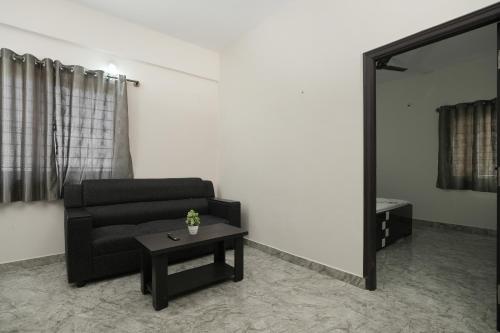 a living room with a black couch and a mirror at Srushti Service apartments in Bengaluru