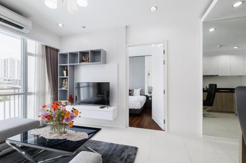 a white living room with a tv and a couch at Shine Sukhumvit 43 Aparthotel Phrompong in Bangkok