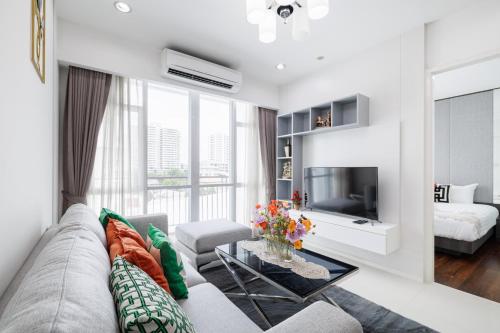 a living room with a couch and a tv at Shine Sukhumvit 43 Aparthotel Phrompong in Bangkok