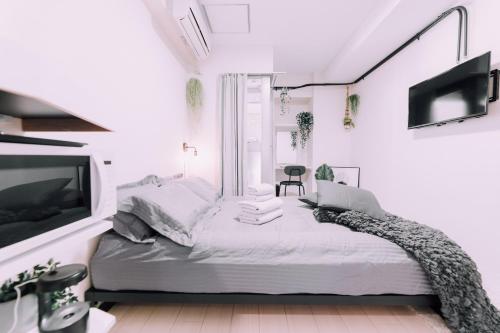 a white bedroom with a bed and a tv at Minimalist Loft Namba Compact Studio with a 24-hour Gym MA502 in Osaka