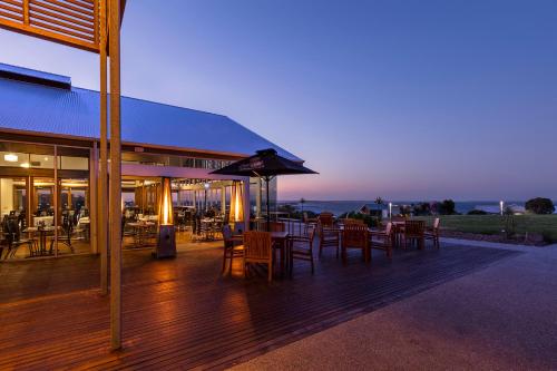 a restaurant with tables and chairs on a deck at night at Silverwater Resort Phillip Island in San Remo