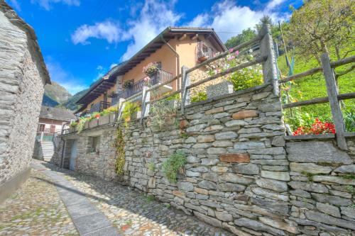 a stone wall with flowers on the side of a building at Ca Contina - Happy Rentals in Frasco