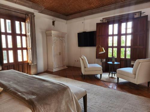 サンミゲル・デ・アジェンデにあるTres Fuentes Dickinson Hotel Boutiqueのベッドと椅子2脚とテレビのある寝室