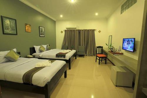 a hotel room with two beds and a television at Sakun House in Siem Reap