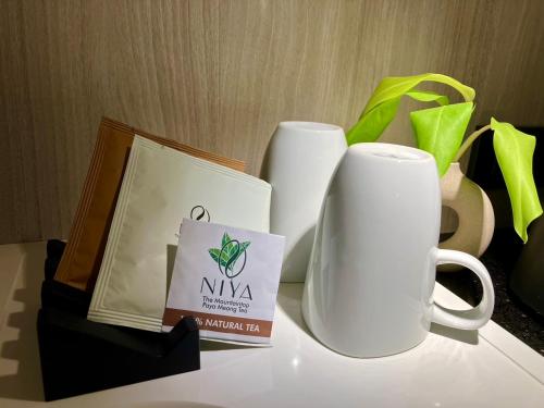 two white coffee mugs and a box on a table at Hotel Clover Asoke - SHA Extra Plus in Bangkok