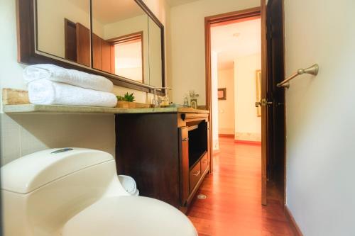 a bathroom with a toilet and a sink and a mirror at Nice Mansion AC 6BR Pool,Básquet,Playground,Games in Envigado