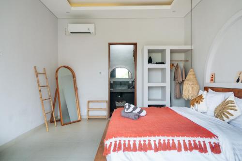 een slaapkamer met een bed met een rode deken bij Casa Nebula Villa in Kerobokan