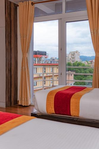 a bedroom with two beds and a large window at Hotel Murano in Pokhara
