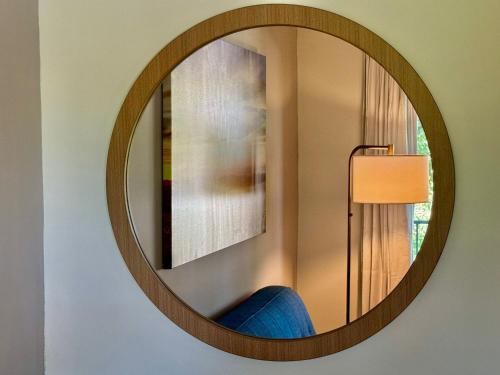a circular mirror on a wall with a blue chair at Nova Inn Resort in Boynton Beach