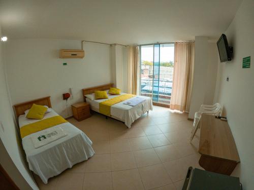 a hotel room with two beds and a window at Hotel los leones Melgar in Melgar