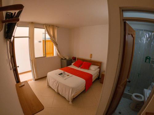 a bedroom with a bed with red pillows at Hotel los leones Melgar in Melgar