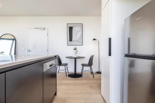 a kitchen with a table and chairs in a room at Hip Condo on Maribyrnong River Cityscape Views! in Melbourne