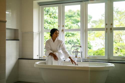 a woman sitting in a bath tub in a bathroom at Ayr Castle 1922 by Reveal in Padukka