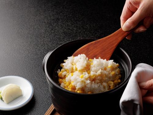 a person holding a wooden spoon over a bowl of rice at Chousenkaku Kameya in Shimo-suwa