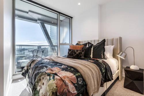 ein Schlafzimmer mit einem Bett und einem großen Fenster in der Unterkunft West Side Spencer St Apt w Marvel Stadium View in Melbourne