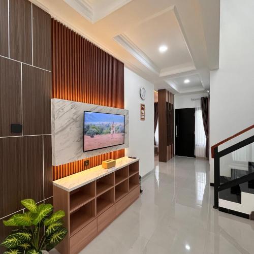 a living room with a flat screen tv on a wall at Hai Homestay by Sampai Coliving in Medari