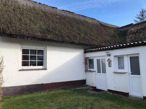 クロスターにあるFerienhaus Präkelの茅葺き屋根と2つのガレージを備えた白い家