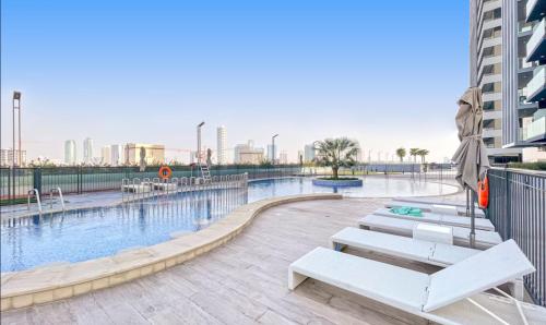 a swimming pool with benches next to a building at Manzil - Stylish living in JVC, City Views and Pool in Dubai