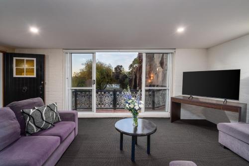 a living room with purple furniture and a flat screen tv at Leisure Inn Penny Royal Hotel & Apartments in Launceston
