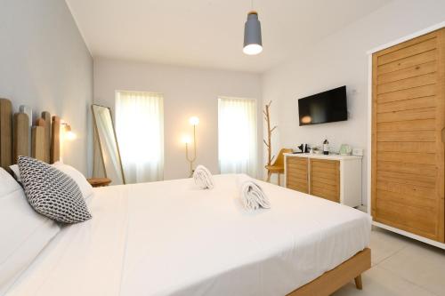a white bedroom with a large white bed and a television at Locanda Carolina Valerio Catullo in Sirmione