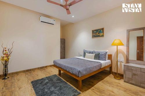 a bedroom with a bed and a ceiling fan at Sundream Palms by VEO - Part of StayVista with Pool, Lawn, BBQ in Alibag