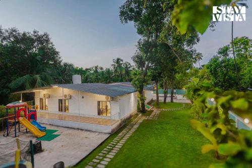 a small house with a playground in the yard at Sundream Palms by VEO - Part of StayVista with Pool, Lawn, BBQ in Alibag