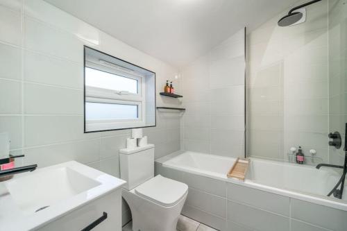 a white bathroom with a toilet and a tub and a sink at New 3BED Stylish Apartment with Amazing Transport in London