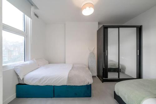 a white bedroom with a bed and a mirror at New 3BED Stylish Apartment with Amazing Transport in London