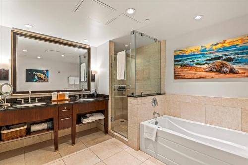 a bathroom with a tub and a sink and a mirror at Honua Kai Hokulani 825 in Lahaina