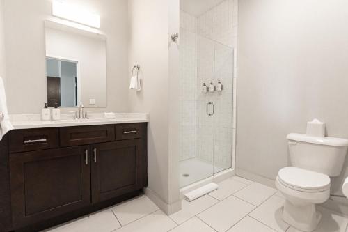 a white bathroom with a toilet and a shower at Kasa Cadillac Square Detroit in Detroit