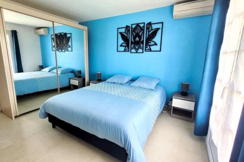 - une chambre bleue avec un lit et un miroir dans l'établissement Appartement spacieux ,4 pers,Piscine & Vue mer, à Antibes