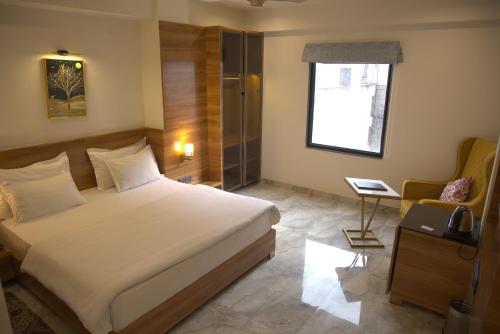 a bedroom with a bed and a chair and a window at Hotel HS Inn Swiming Pool Room in Jaipur