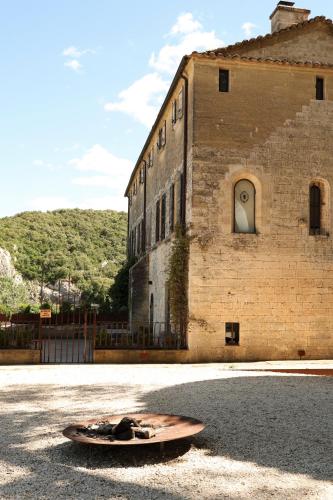 un grand bâtiment en briques avec une roue devant lui dans l'établissement Prieuré Saint-Nicolas - Les Maisons, à Blauzac
