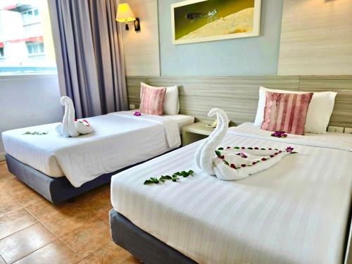 a hotel room with two beds with swans on them at ON Hotel Phuket - SHA in Karon Beach