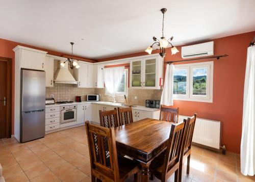 a kitchen with a wooden dining table and chairs at Villa Eudora in Tsoukaladhes