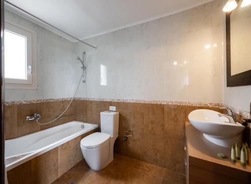 a bathroom with a toilet and a sink and a tub at Villa Eudora in Tsoukaladhes