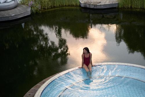 a woman sitting in the water in a swimming pool at Heilthermen Resort Bad Waltersdorf in Bad Waltersdorf