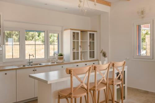 a kitchen with white cabinets and a table and chairs at Villa Annino in Karavados Village with private Pool! in Karavadhos