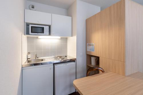 une petite cuisine avec un évier et un micro-ondes dans l'établissement Residhotel St Etienne Centre, à Saint-Étienne
