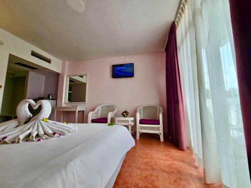 a bedroom with a white bed with two swans on it at ON Hotel Phuket - SHA in Karon Beach