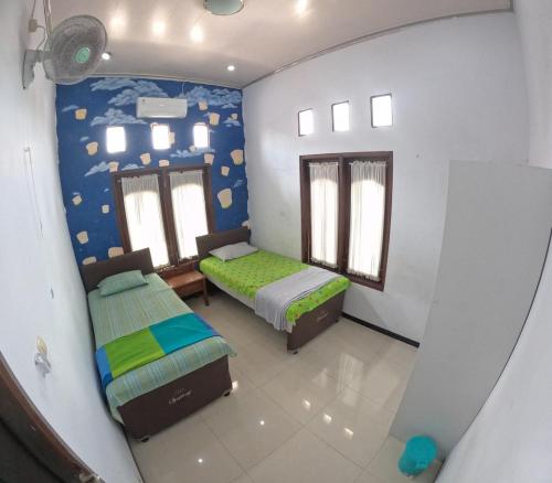 a bedroom with two beds and a wall with planets at Omah Wirokerten Syariah Homestay Jogja in Gondowulung