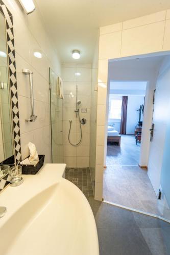 a bathroom with a shower and a sink and a tub at Sporthotel Igls in Innsbruck