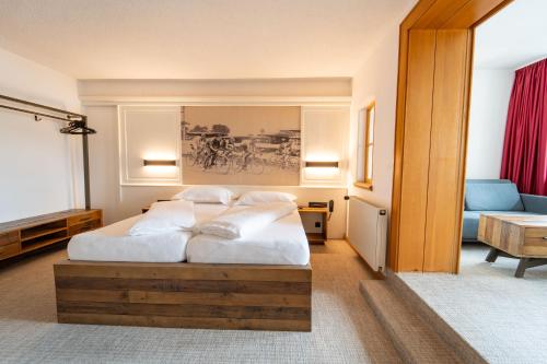 a bedroom with a bed with white sheets and pillows at Sporthotel Igls in Innsbruck