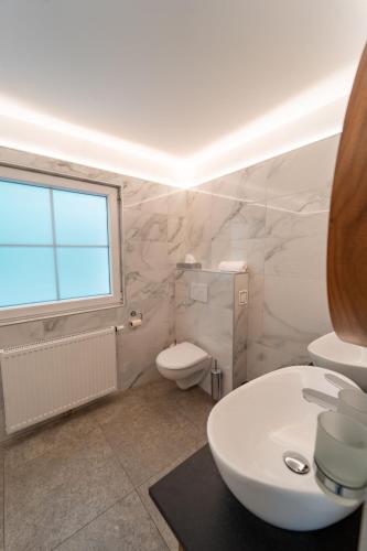 a white bathroom with a toilet and a sink at Sporthotel Igls in Innsbruck