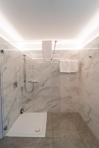 a bathroom with a shower with white marble tiles at Sporthotel Igls in Innsbruck