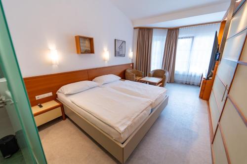 a hotel room with a bed and a chair at Sporthotel Igls in Innsbruck