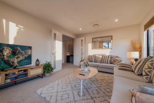 a living room with a couch and a table at Sunlit Sanctuary with Private Patio in Wigram in Christchurch