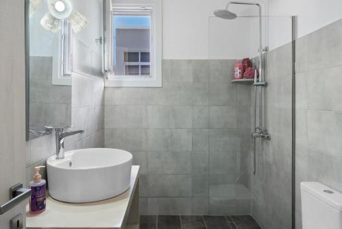 a bathroom with a sink and a shower at Sunset Realty Apartment in Ano Syros